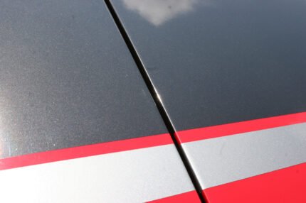 Red C6 Corvette with metallic black and gunmetal ME stripes